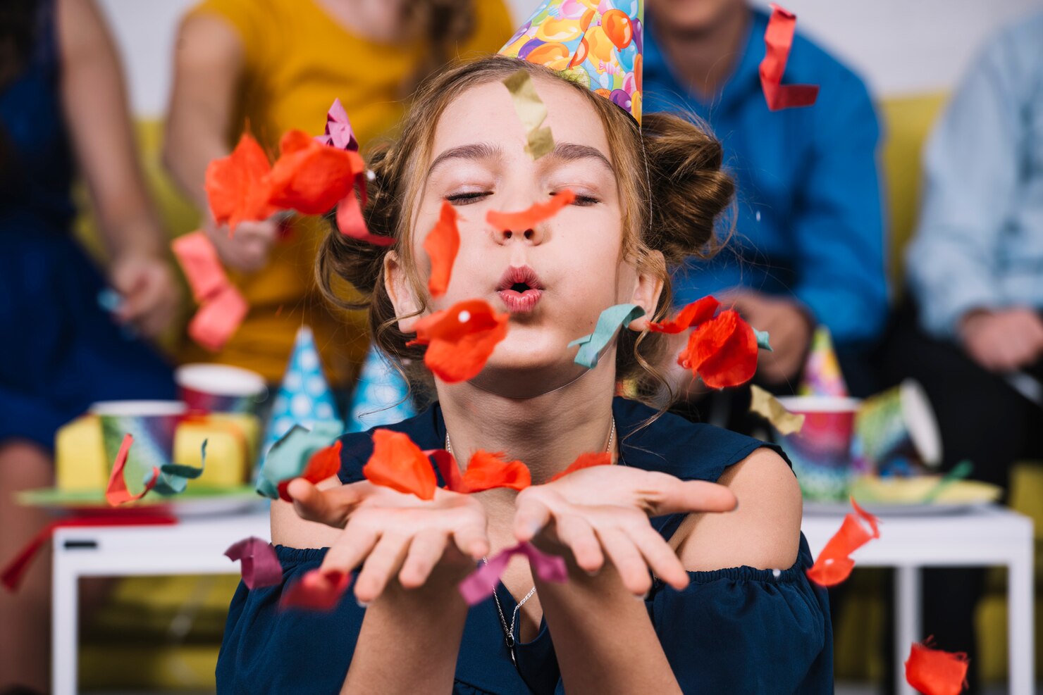 Niña soplando confeti en el día de su cumpleaños.